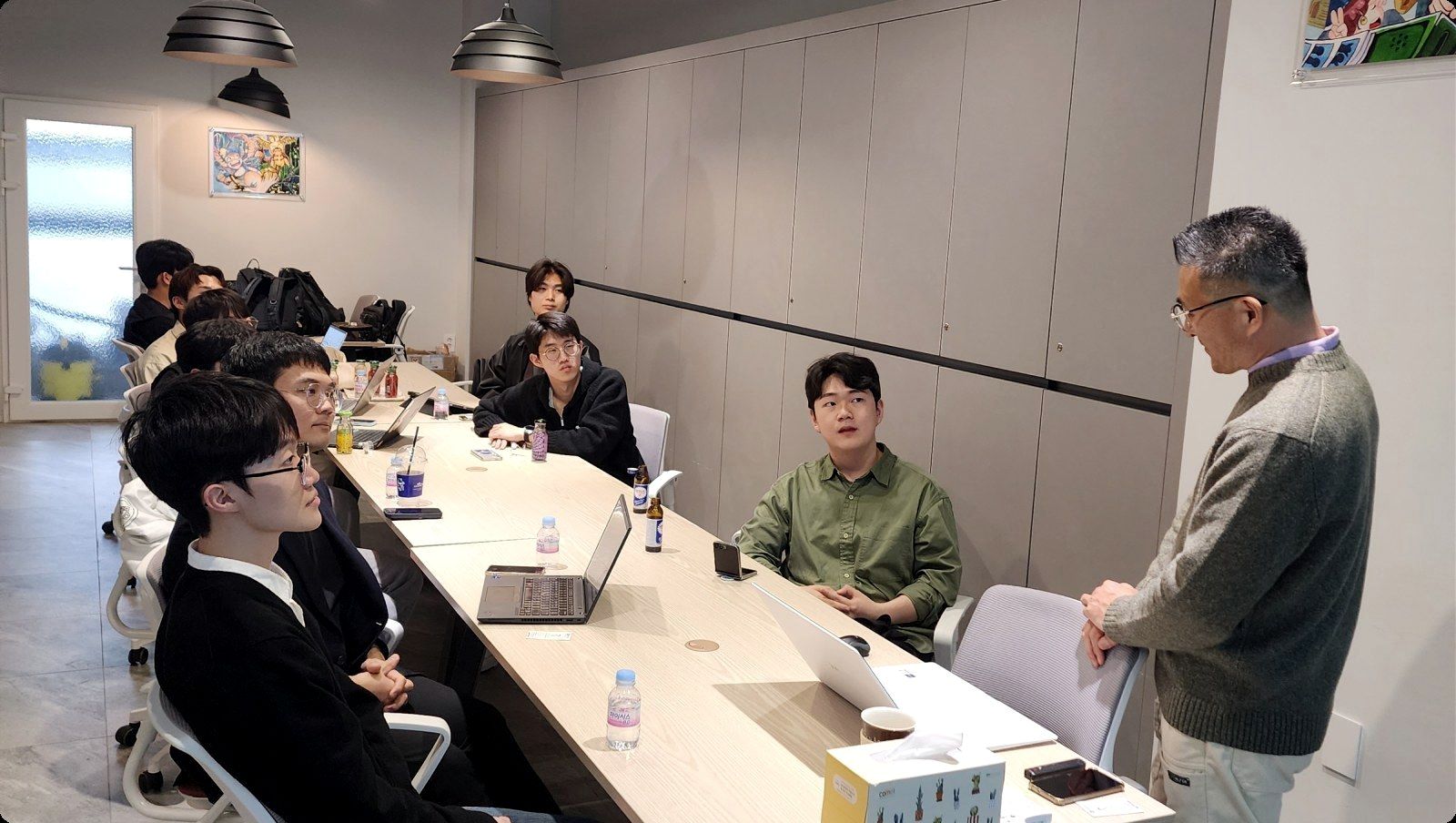 회의실에서 기업 대표의 설명을 듣는 동아리원들